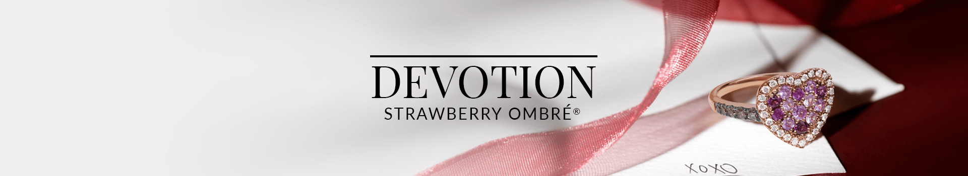 Heart-shaped pavé ring featuring a gradient of pink to purple gemstones surrounded by diamonds, resting on a love letter with pink ribbon, from Le Vian’s Devotion Strawberry Ombré® collection.