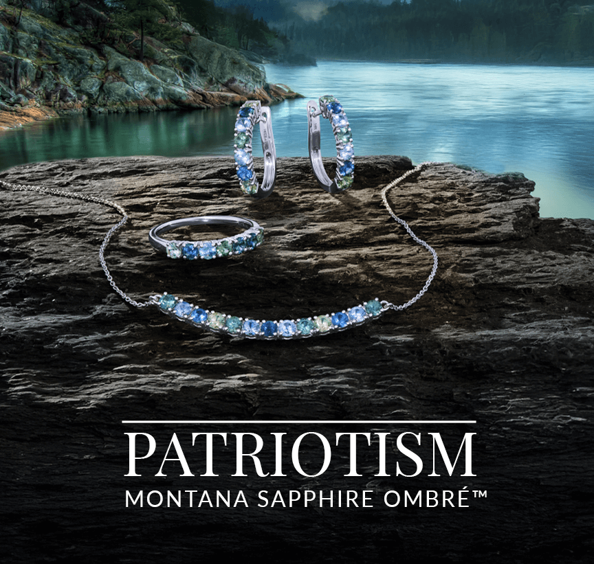 Necklace, earrings, and ring set with Montana Sapphire Ombré™ gemstones resting on rugged rock by a tranquil body of water, from Le Vian’s Patriotism collection.