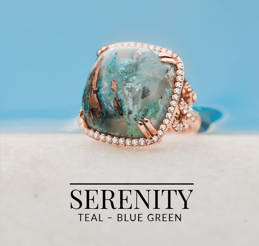 Cushion-cut teal-blue green Aquapraise® gemstone ring with rose gold and diamond setting, placed on a soft sand surface with a calm ocean blue background.