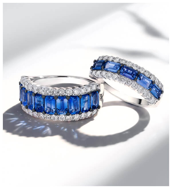 Two white gold blue sapphire and diamond rings with rectangular blue sapphires framed by white diamonds, photographed on a bright white background.