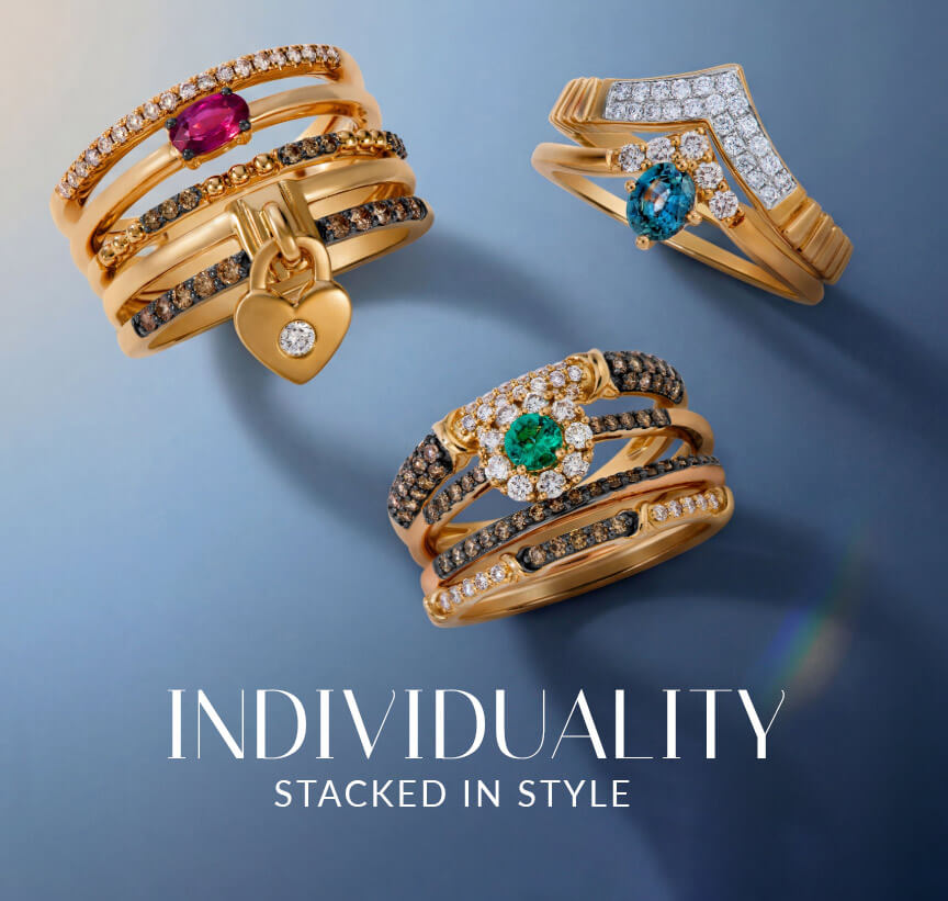 Le Vian® stacked rings in gold with colorful gemstones, white diamonds and Chocolate Diamonds® on a blue background.