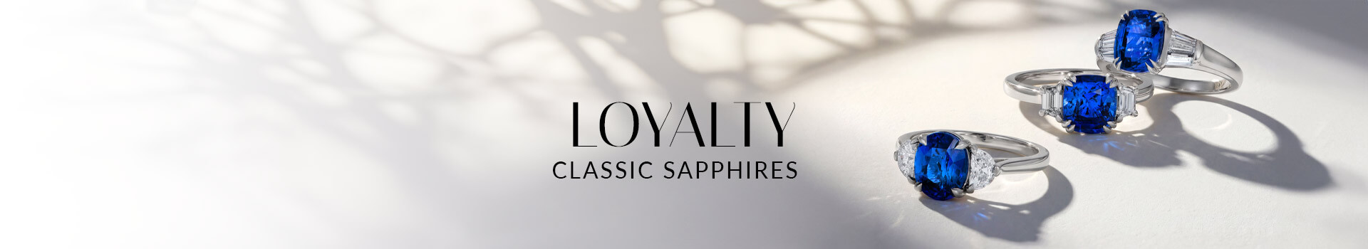 Three Le Vian® sapphire rings with diamond side stones in white metal on a softly lit white surface.